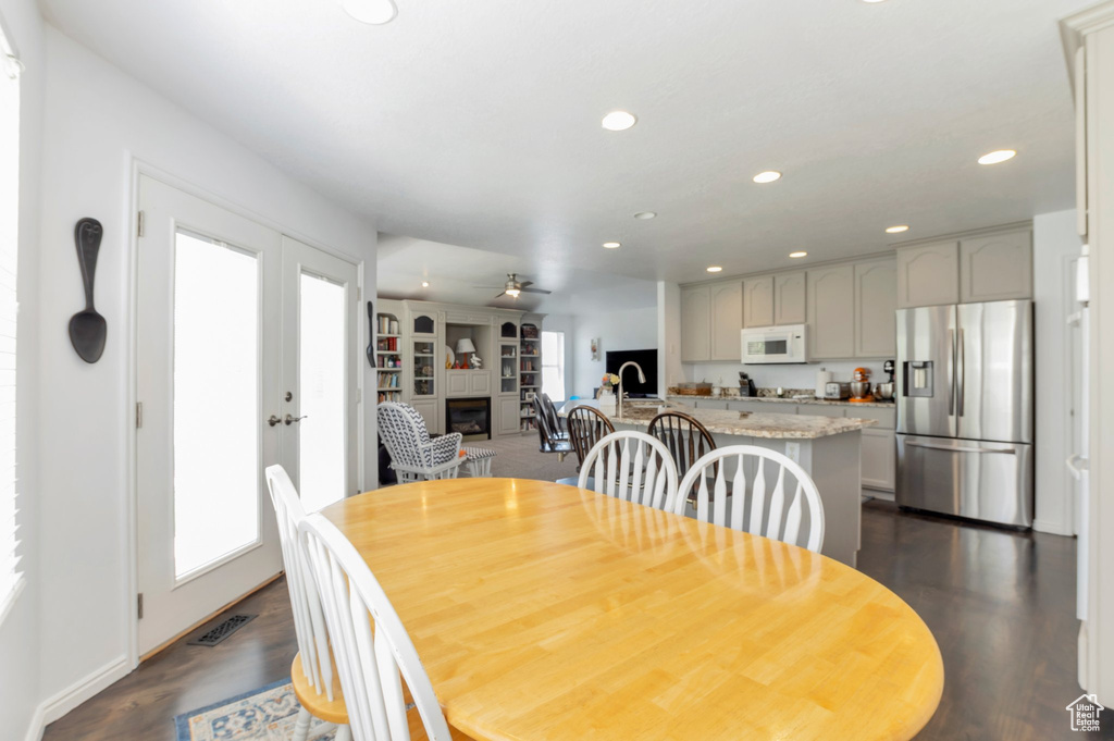 Dining room with a glass covered fireplace, recessed lighting, ceiling fan, baseboards, and dark wood finished floors