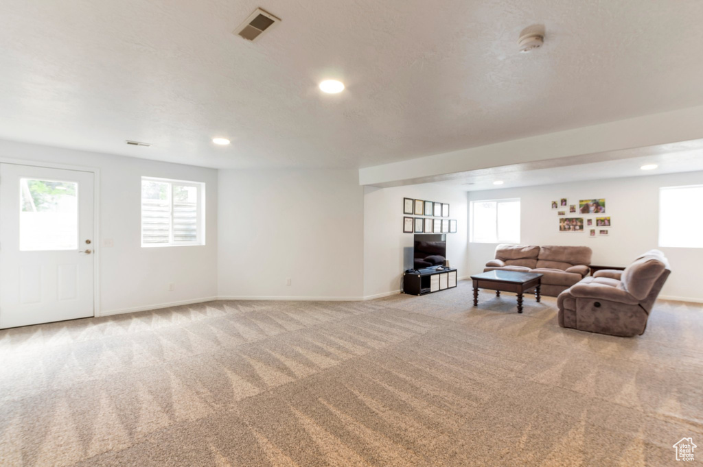 Carpeted living area featuring recessed lighting, plenty of natural light, and baseboards