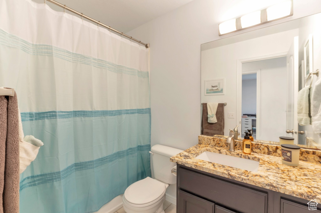 Bathroom featuring toilet, vanity, and curtained shower