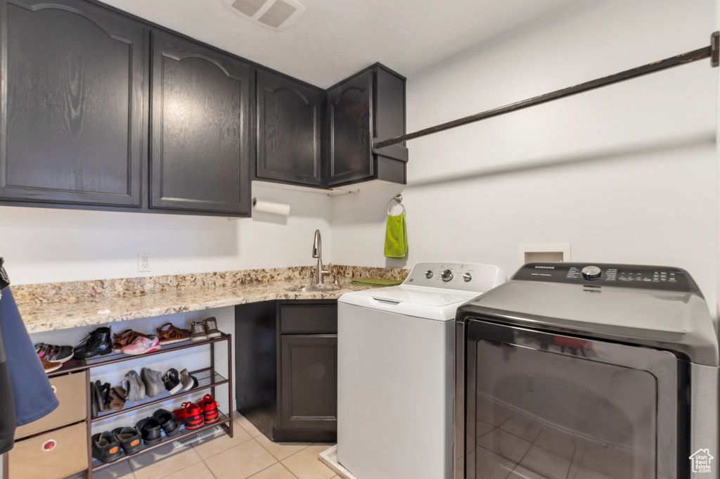 Washroom featuring independent washer and dryer, cabinet space, and light tile patterned flooring
