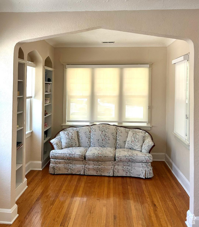 Living area with wood-type flooring, arched walkways, and baseboards
