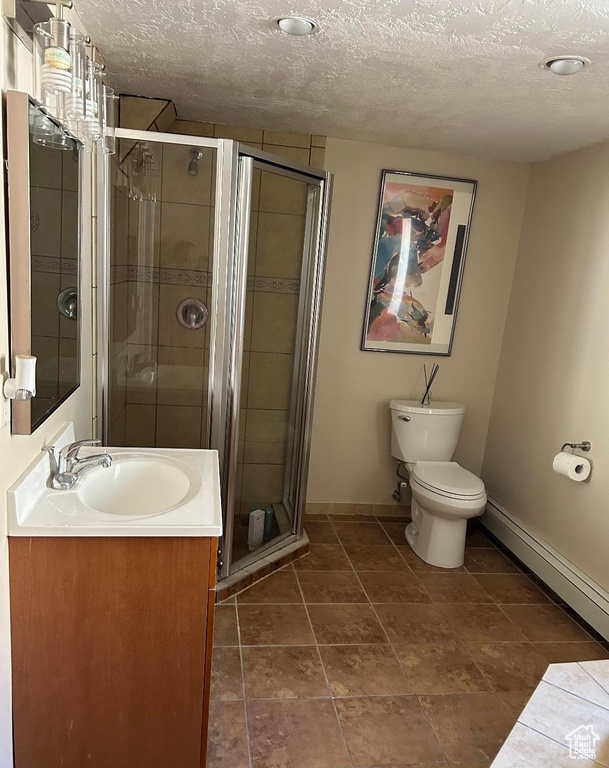 Full bathroom featuring baseboards, vanity, a textured ceiling, a shower stall, and toilet