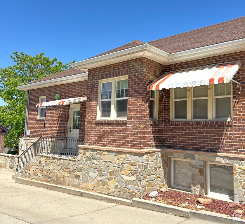 View of front of home with brick siding, stone siding, and roof with shingles
