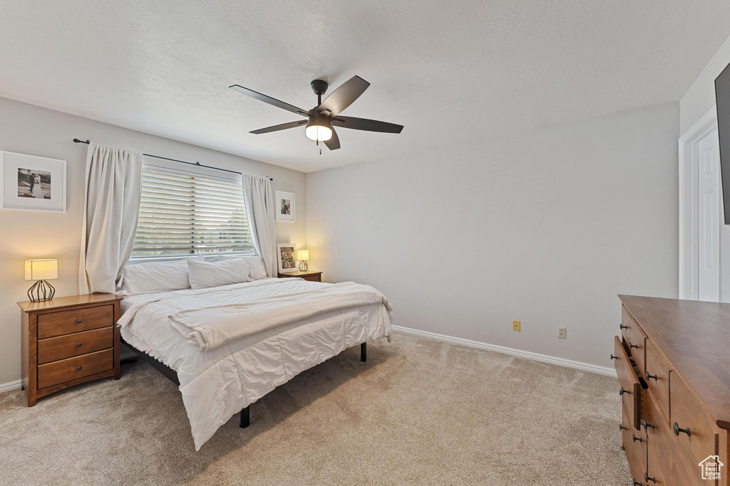 Bedroom featuring light carpet, baseboards, and ceiling fan