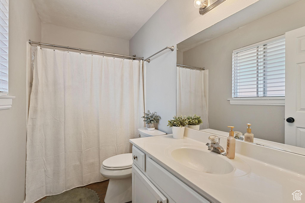 Bathroom with vanity, toilet, curtained shower, and tile patterned flooring