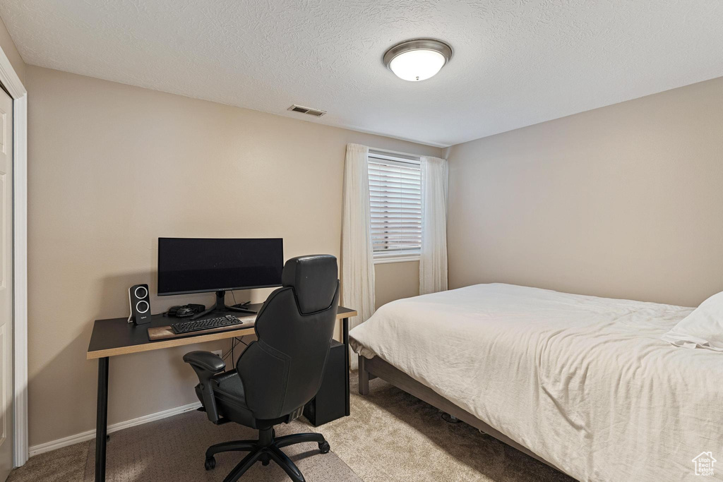 Bedroom with carpet, an office area, a textured ceiling, and baseboards
