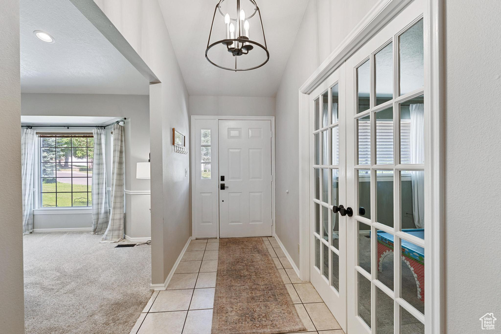 Entrance foyer featuring french doors, a chandelier, light tile patterned floors, and baseboards