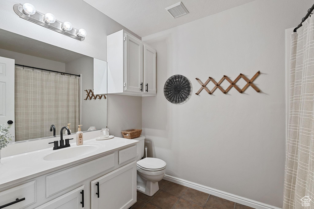 Full bathroom with toilet, vanity, tile patterned flooring, and baseboards