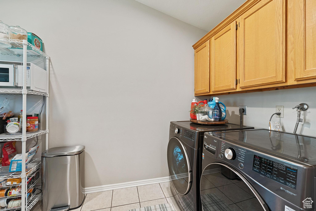 Laundry area with cabinet space, independent washer and dryer, baseboards, and light tile patterned floors