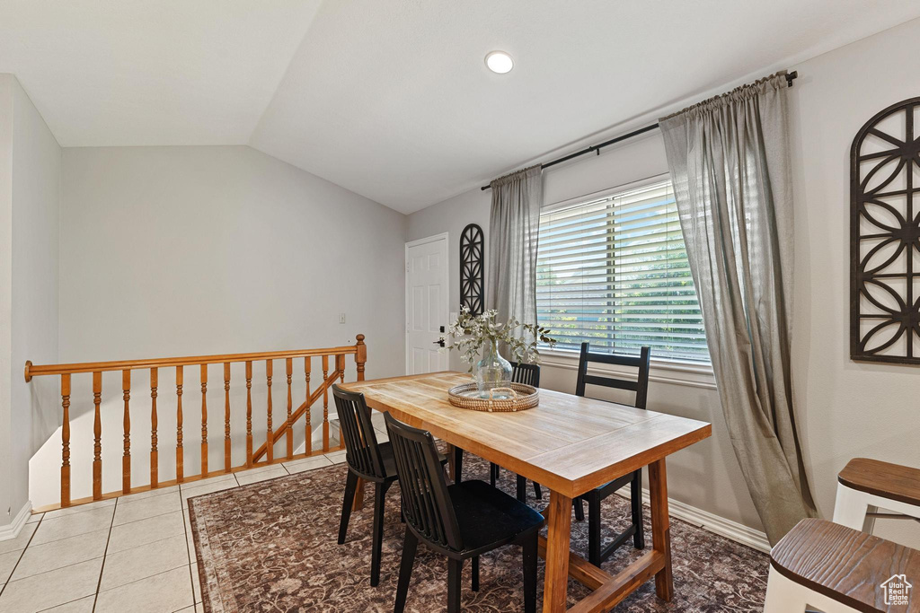 Dining space featuring light tile patterned floors, vaulted ceiling, and baseboards