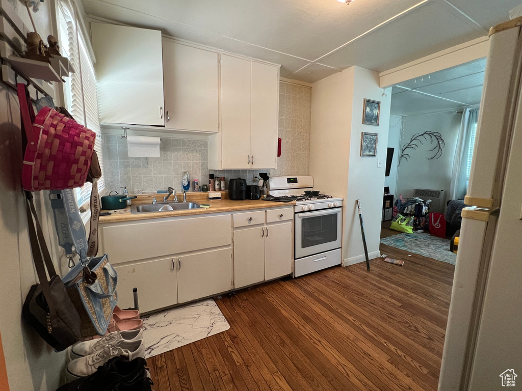 Kitchen featuring white appliances, a sink, dark wood-type flooring, and white cabinets
