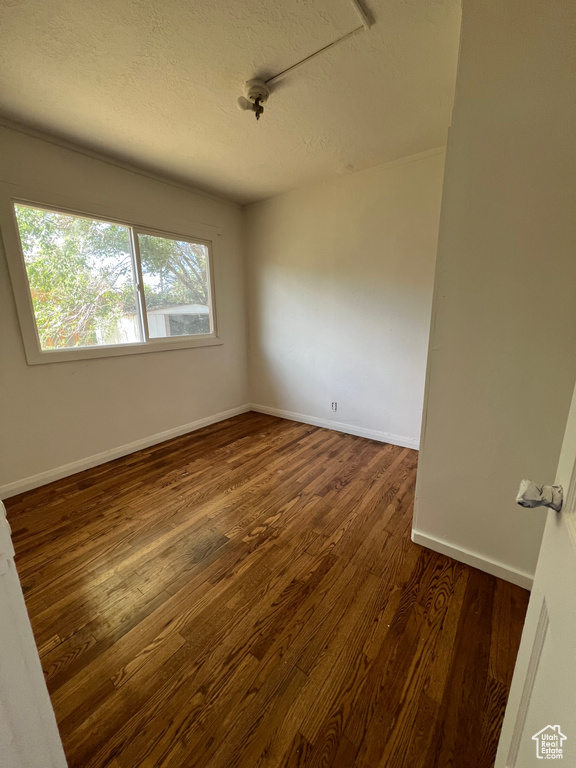 Unfurnished room with dark wood-style floors, a textured ceiling, and baseboards