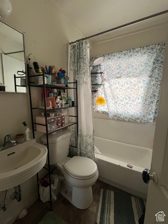 Bathroom with toilet, shower / bathtub combination with curtain, and a sink