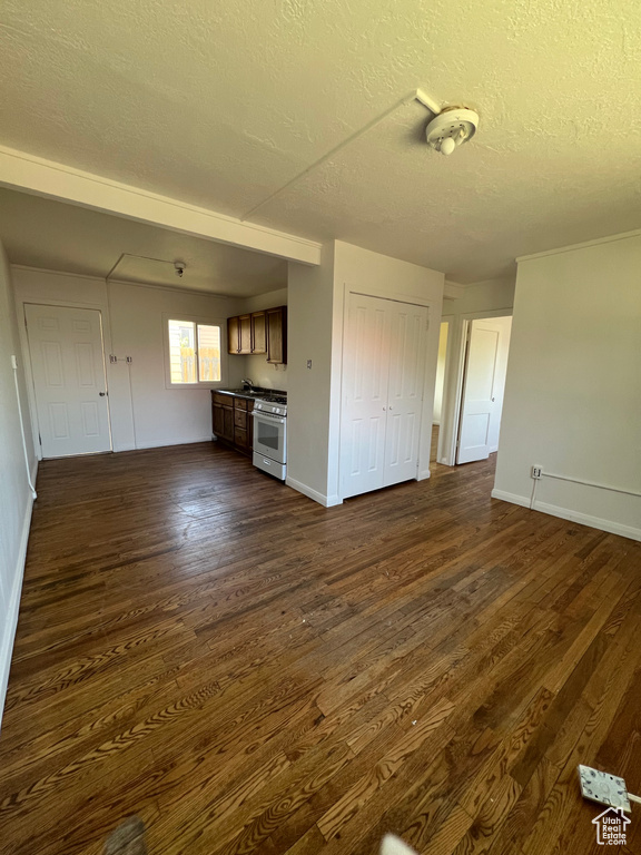 Unfurnished living room with a textured ceiling, dark wood-type flooring, and baseboards