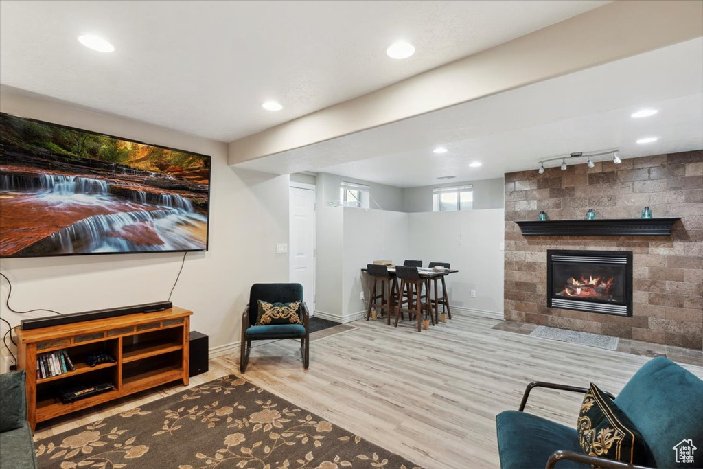 Living room featuring wood finished floors, rail lighting, baseboards, a fireplace, and recessed lighting