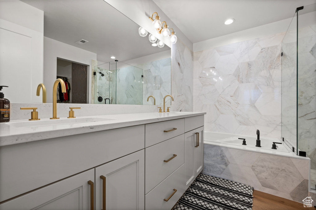 Full bathroom featuring double vanity, a garden tub, and a marble finish shower