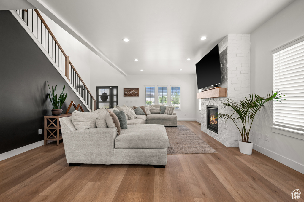 Living area featuring a fireplace, light wood finished floors, recessed lighting, baseboards, and stairs