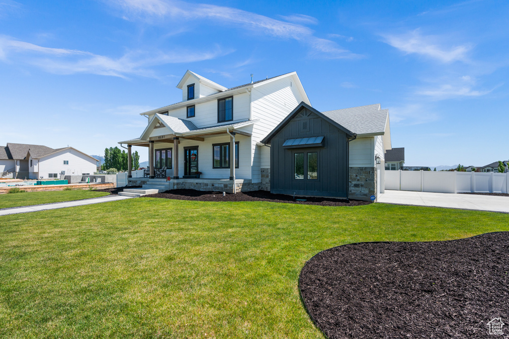 Modern farmhouse style home featuring covered porch, stone siding, and board and batten siding