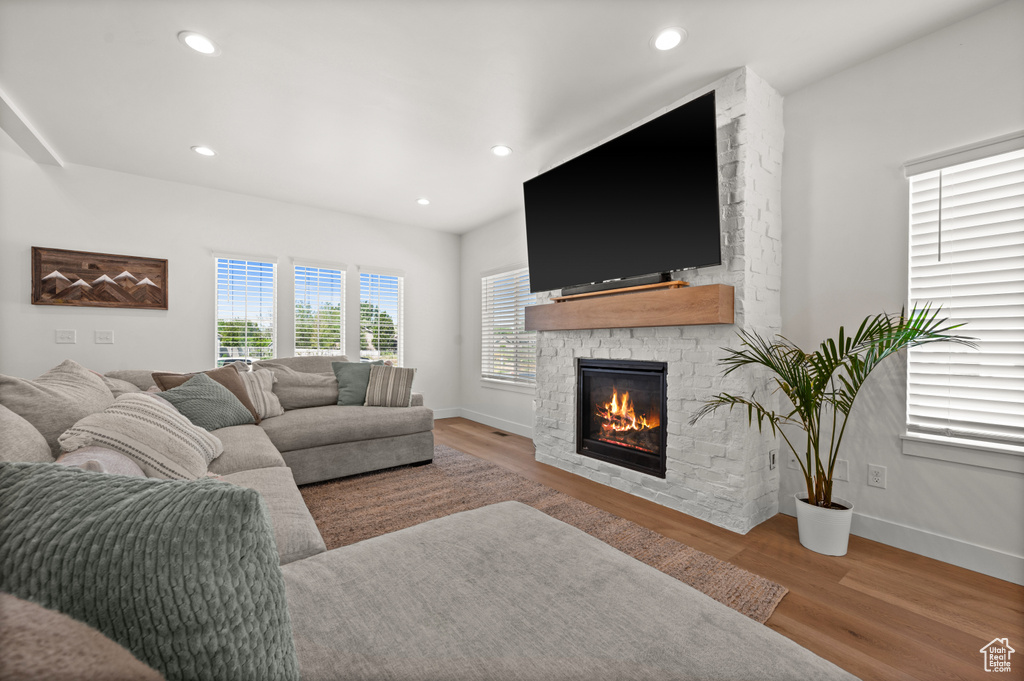 Living area with a stone fireplace, wood finished floors, baseboards, and recessed lighting