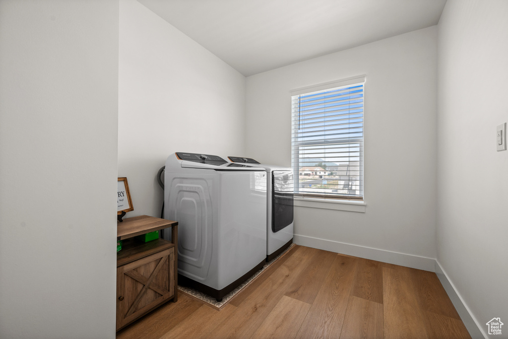 Washroom featuring washer and clothes dryer, light wood-type flooring, and baseboards