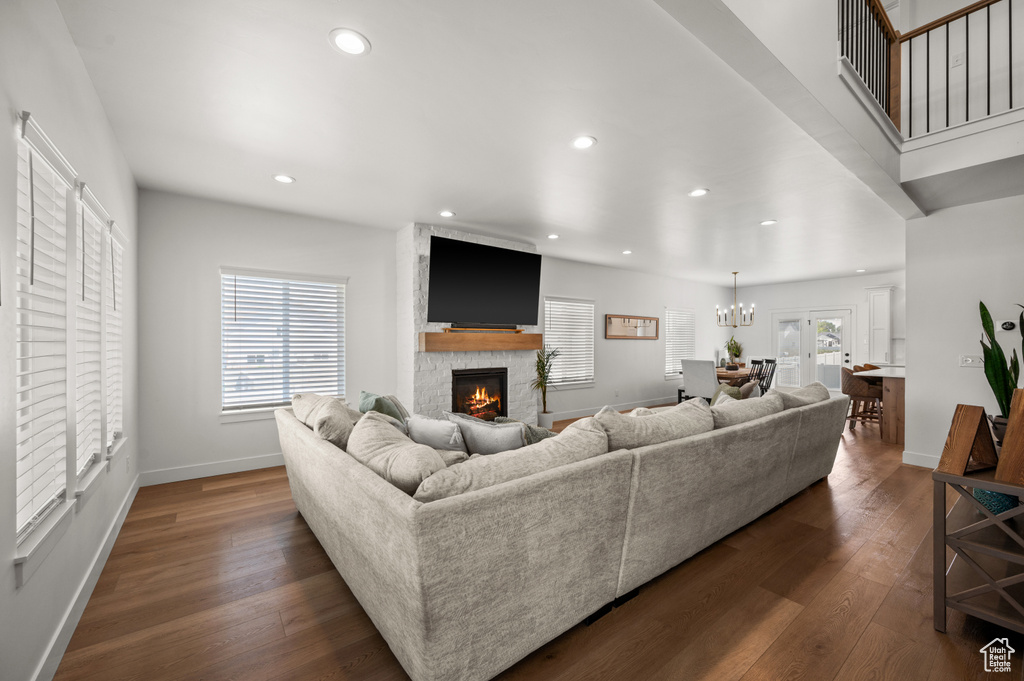 Living area featuring dark wood-style floors, recessed lighting, a fireplace, baseboards, and a chandelier