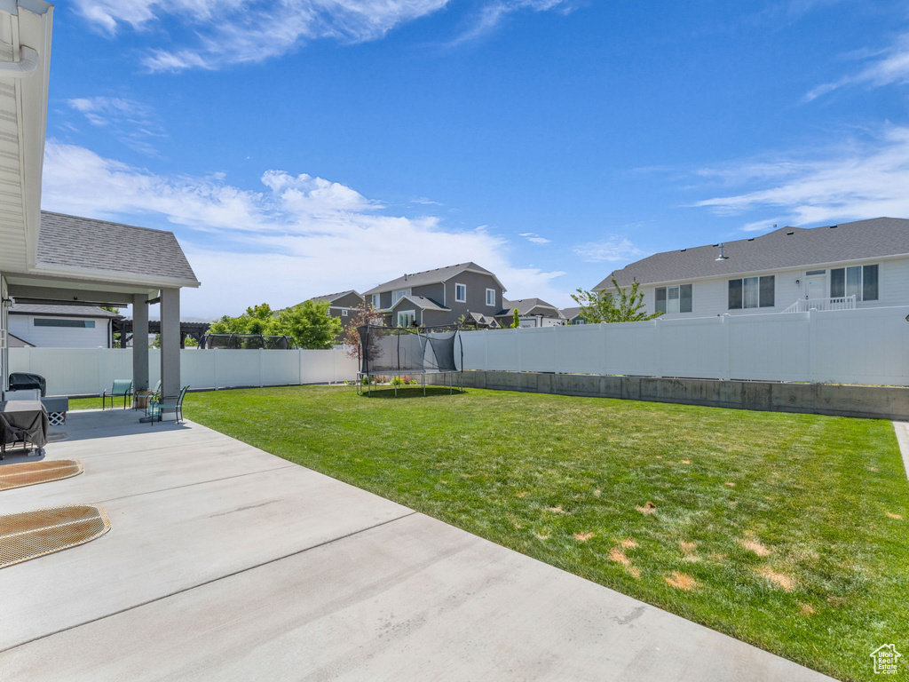 View of yard featuring a trampoline, a patio area, and a residential view