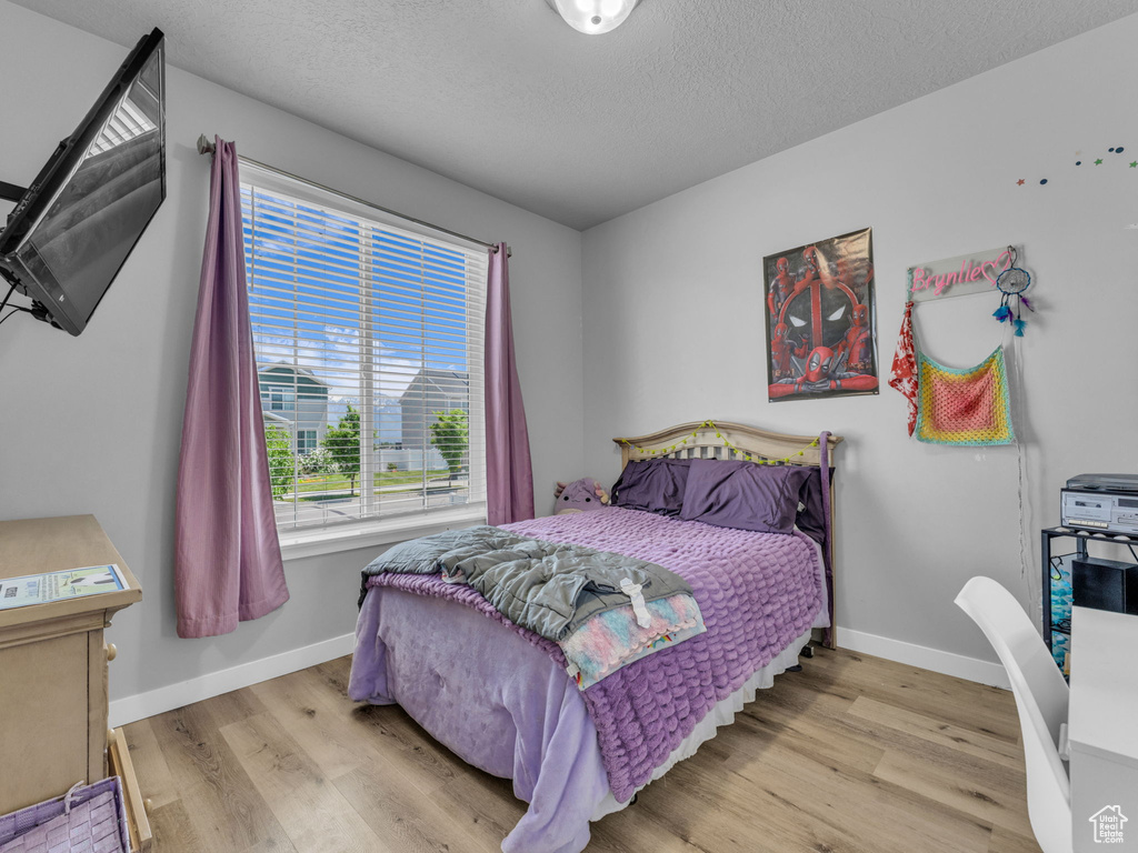 Bedroom featuring wood finished floors, baseboards, and a textured ceiling