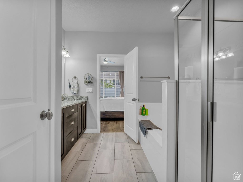 Bathroom with vanity, connected bathroom, ceiling fan, and a shower stall