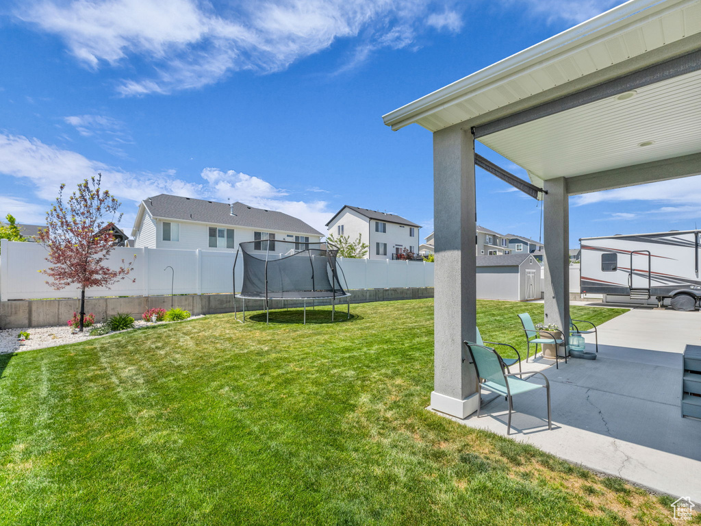 View of yard featuring a trampoline, a patio area, and a residential view