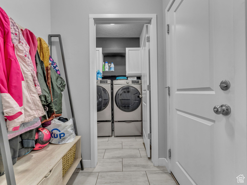 Washroom featuring independent washer and dryer, cabinet space, and light marble finish flooring