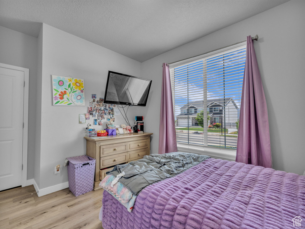 Bedroom featuring light wood-style flooring, baseboards, and a textured ceiling