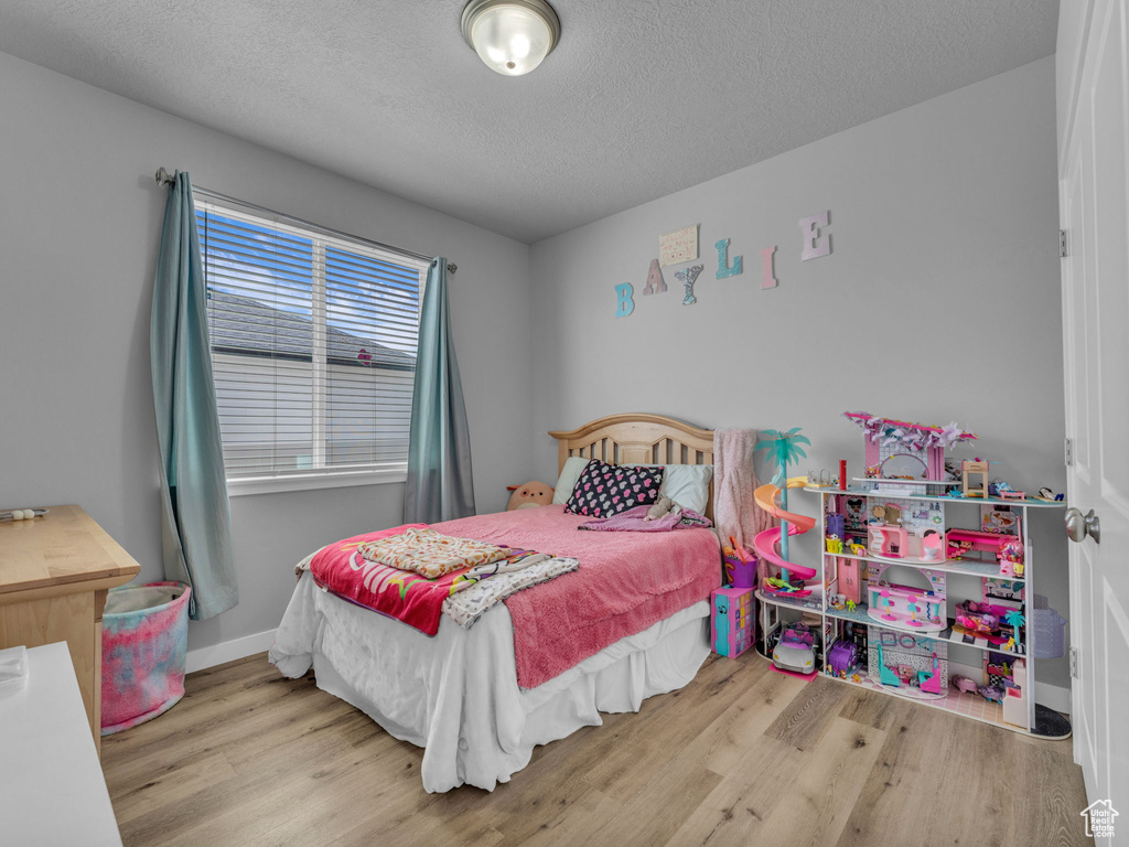 Bedroom with wood finished floors and a textured ceiling