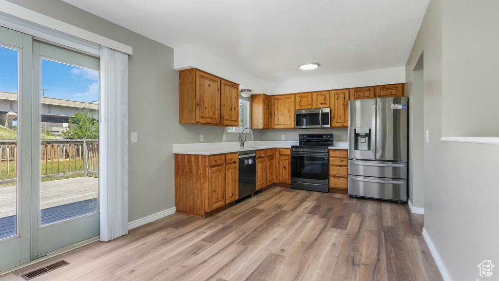 Kitchen featuring appliances with stainless steel finishes, light countertops, wood finished floors, and healthy amount of natural light
