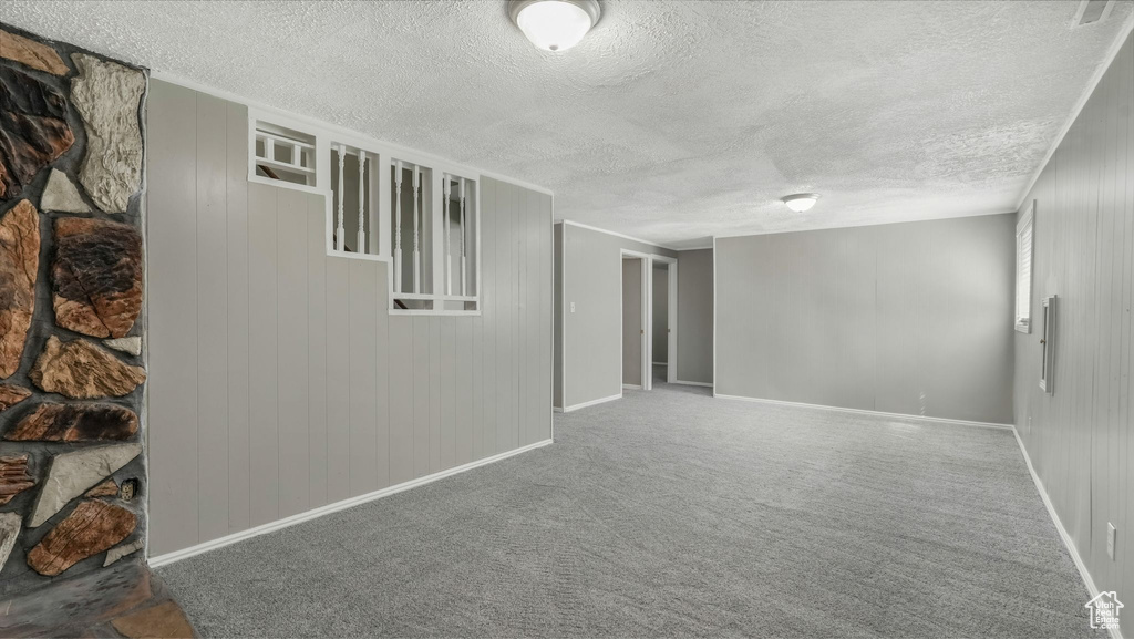 Unfurnished room with baseboards, a textured ceiling, and carpet floors