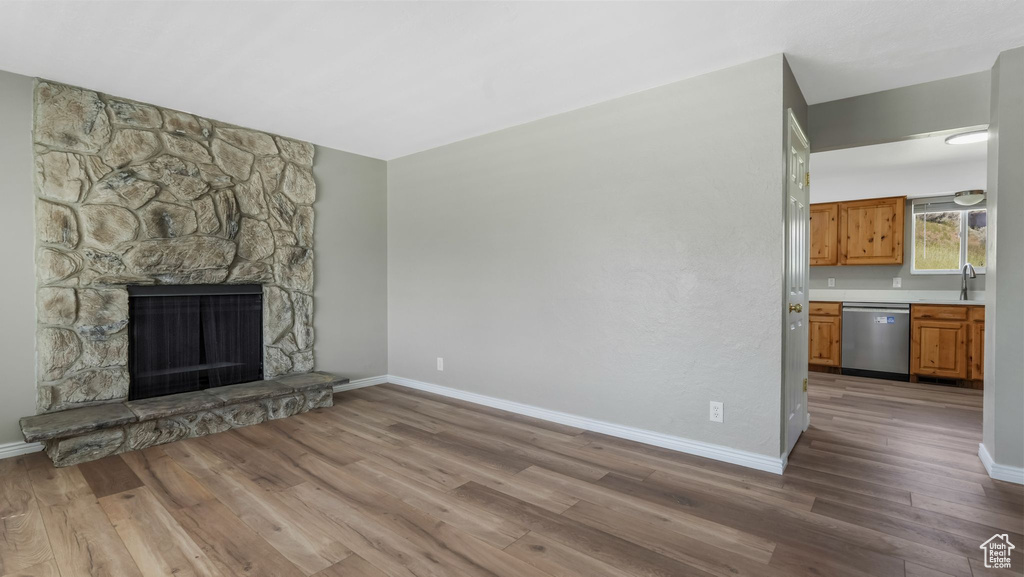 Unfurnished living room featuring a sink, wood finished floors, baseboards, and a fireplace