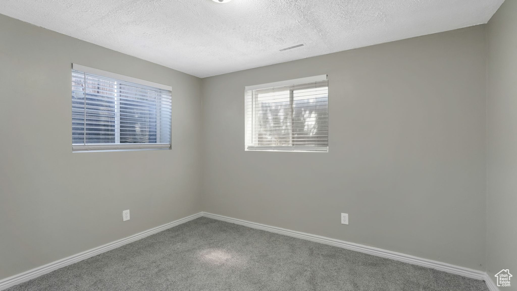 Carpeted empty room with baseboards and a textured ceiling