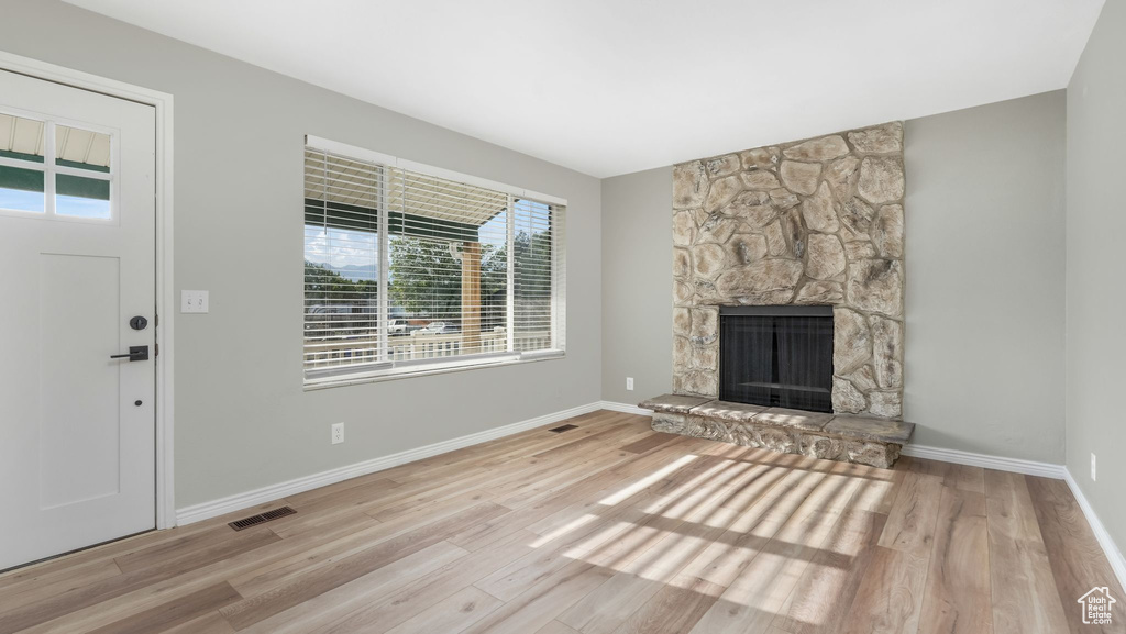 Unfurnished living room with wood finished floors, a fireplace, and baseboards