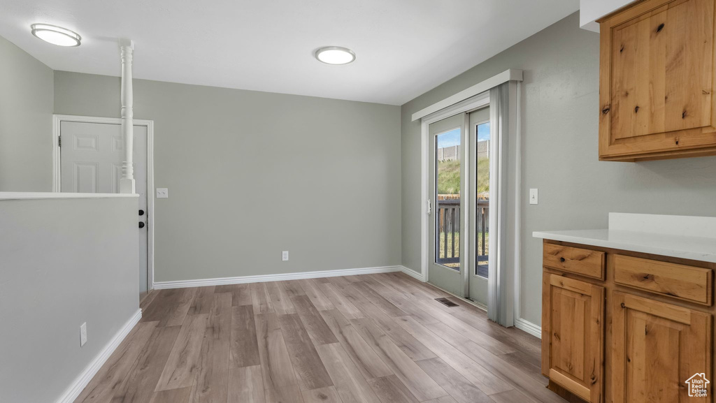 Unfurnished dining area with light wood-style flooring and baseboards