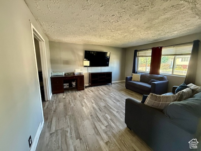 Living room with a textured ceiling, wood finished floors, and baseboards