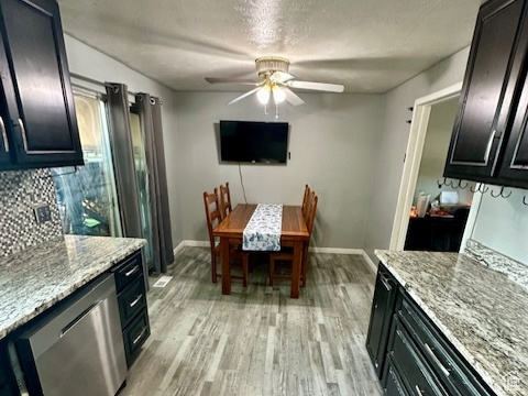 Kitchen with stainless steel dishwasher, a textured ceiling, light wood finished floors, ceiling fan, and baseboards