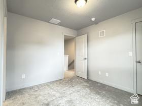 Unfurnished bedroom with a textured ceiling, carpet floors, and baseboards