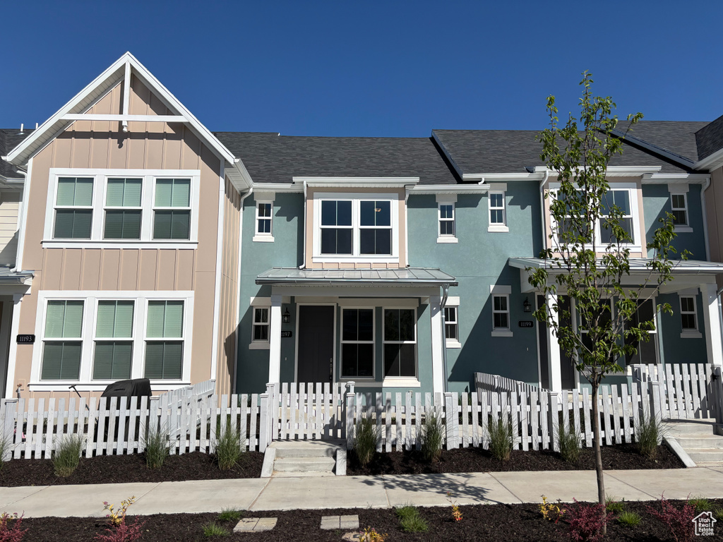 View of front of property featuring a fenced front yard, a shingled roof, board and batten siding, and covered porch