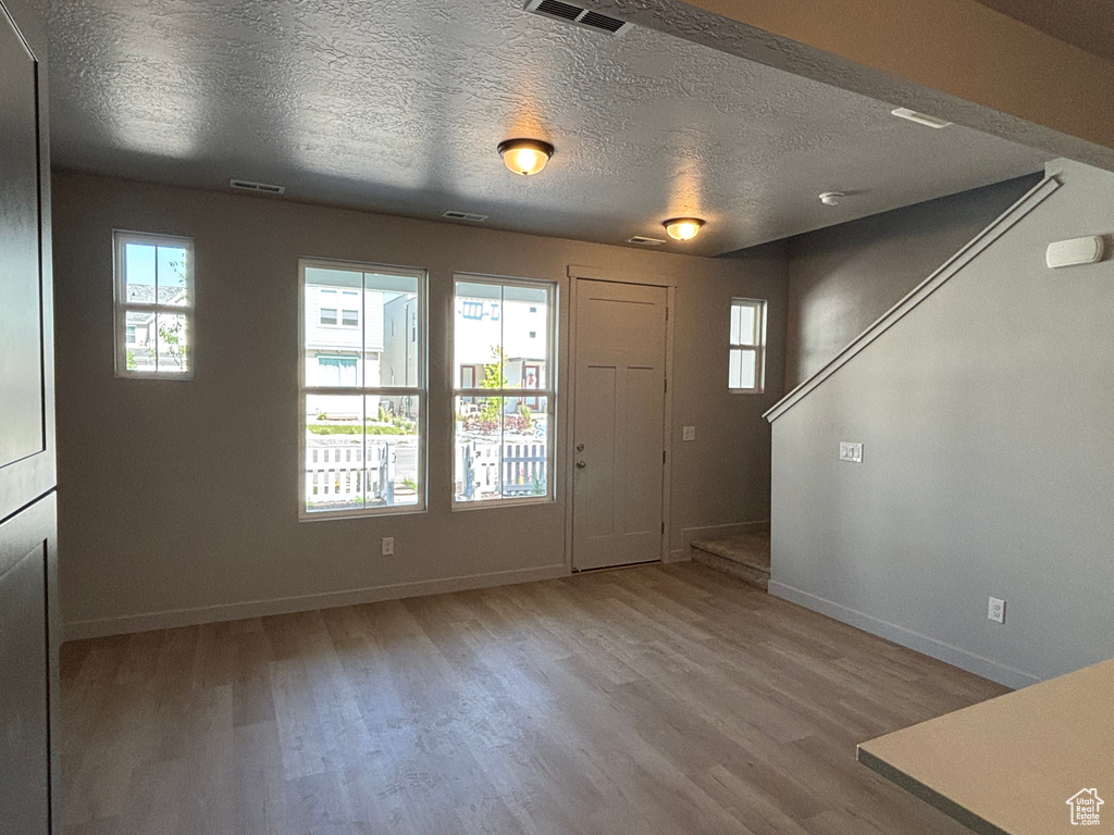 Entrance foyer featuring baseboards, wood finished floors, and a textured ceiling