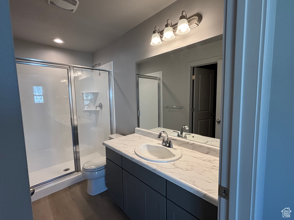 Full bathroom with toilet, a stall shower, vanity, and recessed lighting