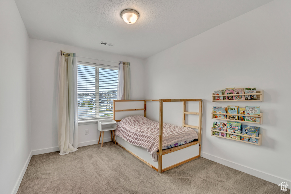Bedroom featuring carpet flooring, baseboards, and a textured ceiling