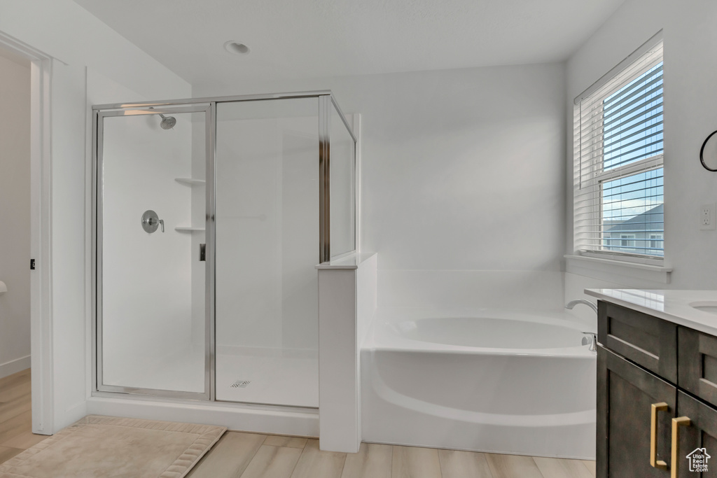 Bathroom with a shower stall, a garden tub, vanity, and wood finished floors