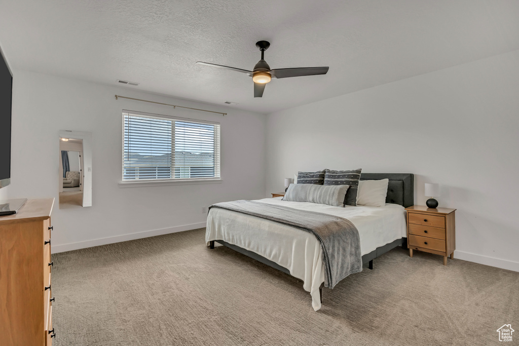 Bedroom with baseboards, light colored carpet, ceiling fan, and a textured ceiling