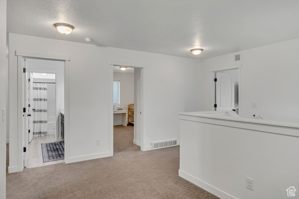 Unfurnished room with light colored carpet, baseboards, a textured ceiling, and a smoke detector