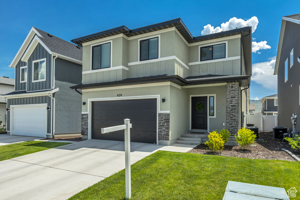 View of front of home with stone siding, a garage, board and batten siding, and driveway