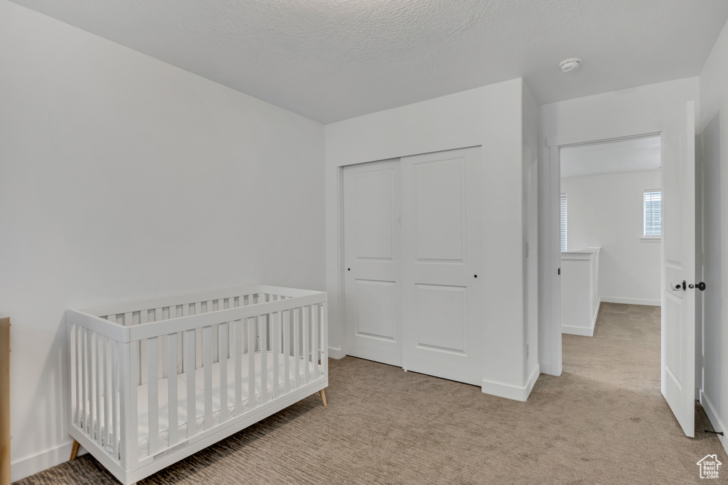 Bedroom featuring a closet, light colored carpet, and baseboards